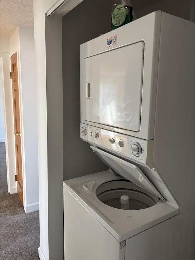 clothes washing area with stacked washing maching and dryer, carpet, and a textured ceiling