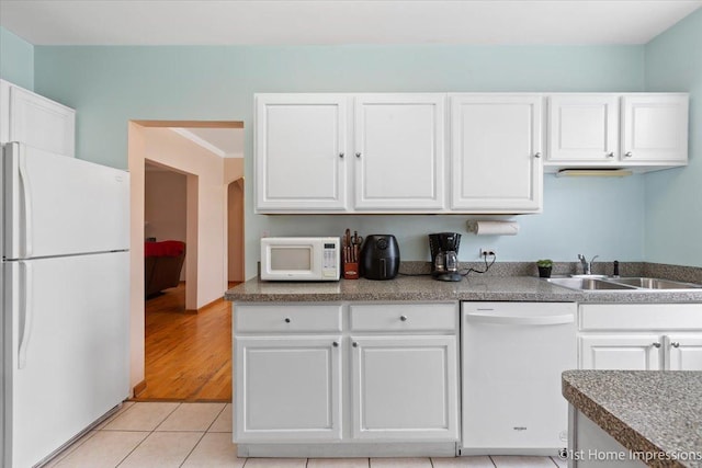 kitchen with light tile patterned flooring, white appliances, sink, and white cabinets