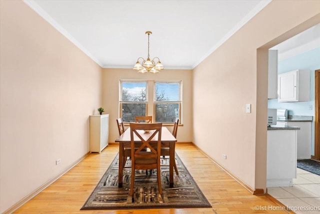 dining space featuring ornamental molding, a notable chandelier, and light wood-type flooring