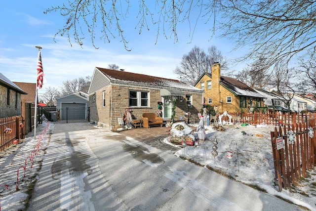 snow covered rear of property featuring a garage and an outbuilding