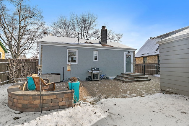 snow covered rear of property featuring a hot tub and a patio