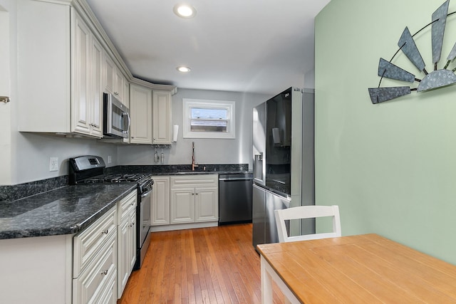 kitchen featuring stainless steel appliances, white cabinetry, sink, and light hardwood / wood-style floors