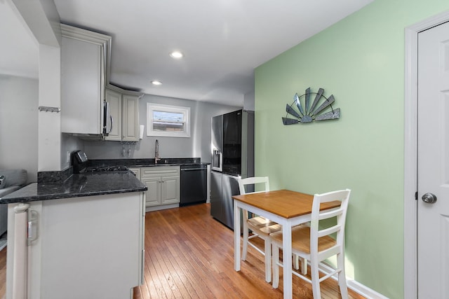 kitchen with stainless steel appliances, wood-type flooring, sink, and kitchen peninsula