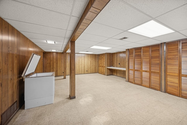 finished below grade area with visible vents, wooden walls, and tile patterned floors