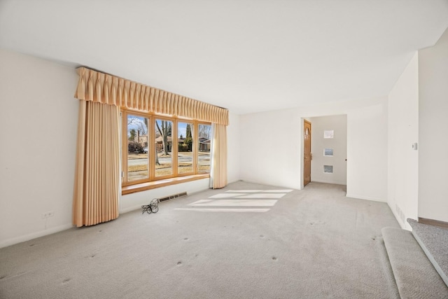 spare room featuring carpet floors, stairway, baseboards, and visible vents