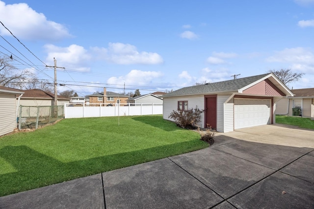 view of yard featuring a garage, fence, and an outbuilding