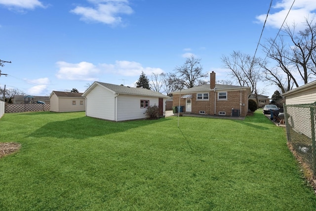 back of property featuring a chimney, fence, a yard, central air condition unit, and an outdoor structure