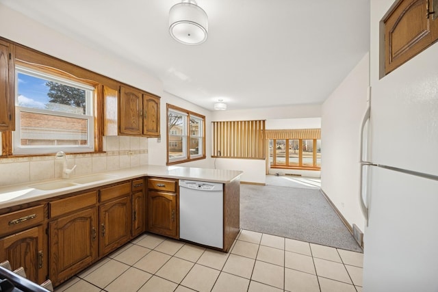 kitchen with a peninsula, white appliances, plenty of natural light, and a sink