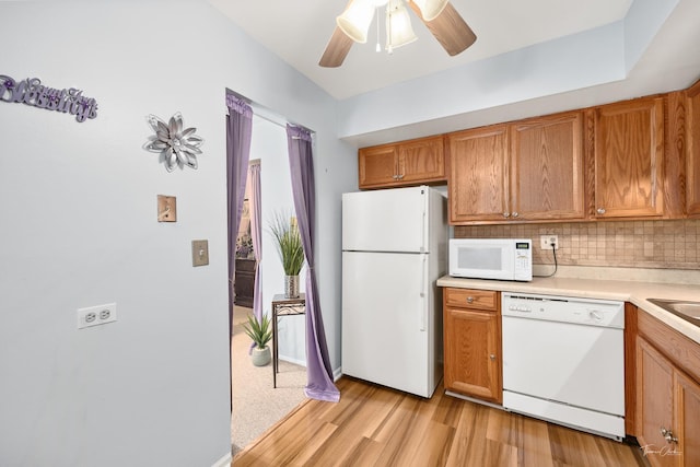 kitchen with tasteful backsplash, sink, ceiling fan, white appliances, and light hardwood / wood-style flooring