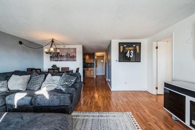 living room featuring hardwood / wood-style flooring, an inviting chandelier, and a textured ceiling