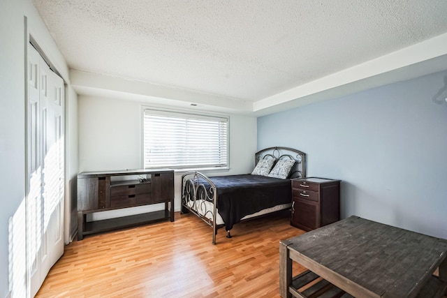 bedroom with a closet, light hardwood / wood-style floors, and a textured ceiling