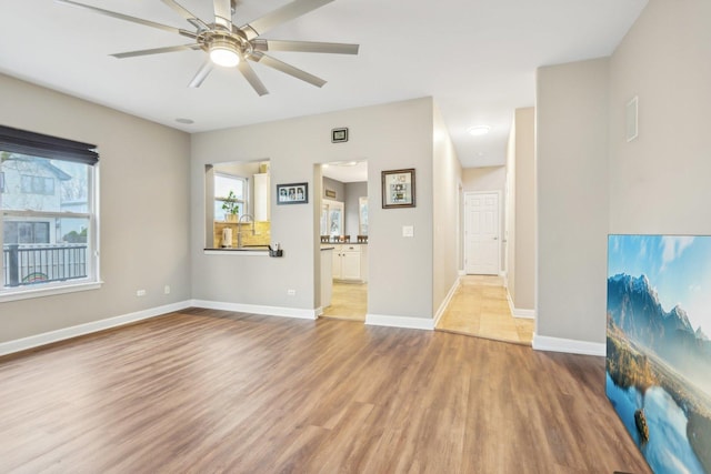 unfurnished living room with ceiling fan, sink, and light hardwood / wood-style floors