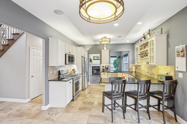 kitchen featuring sink, appliances with stainless steel finishes, a kitchen breakfast bar, white cabinets, and kitchen peninsula