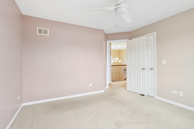 unfurnished bedroom featuring ceiling fan with notable chandelier and light carpet