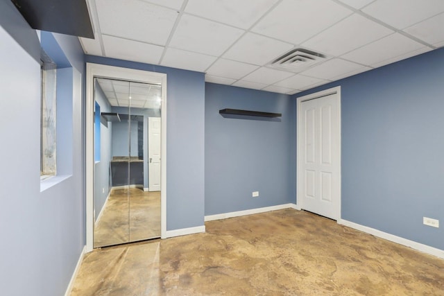 unfurnished bedroom with a paneled ceiling and concrete flooring