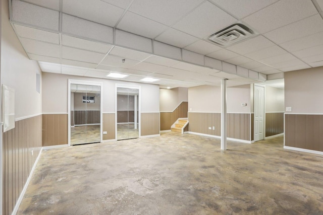 basement with wood walls and a drop ceiling