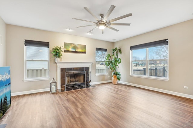 unfurnished living room with ceiling fan, hardwood / wood-style floors, and a fireplace