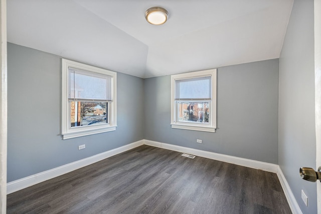 unfurnished room with lofted ceiling, dark hardwood / wood-style flooring, and a wealth of natural light