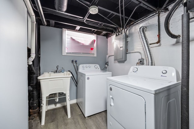 washroom featuring hardwood / wood-style flooring, washing machine and dryer, and electric panel