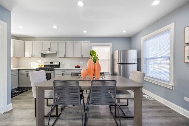 kitchen featuring gray cabinets, appliances with stainless steel finishes, a breakfast bar, backsplash, and a center island