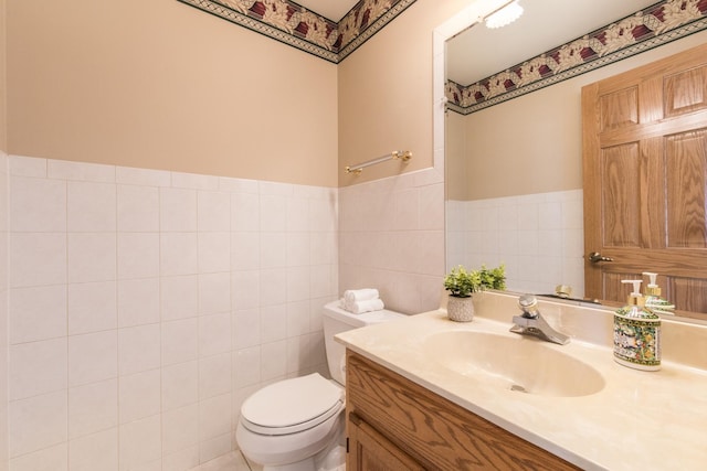 bathroom with vanity, tile walls, and toilet