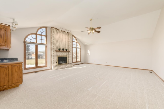 unfurnished living room featuring ceiling fan, light colored carpet, lofted ceiling, and a brick fireplace