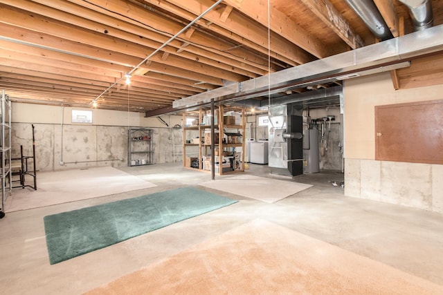 basement featuring heating unit, separate washer and dryer, and water heater