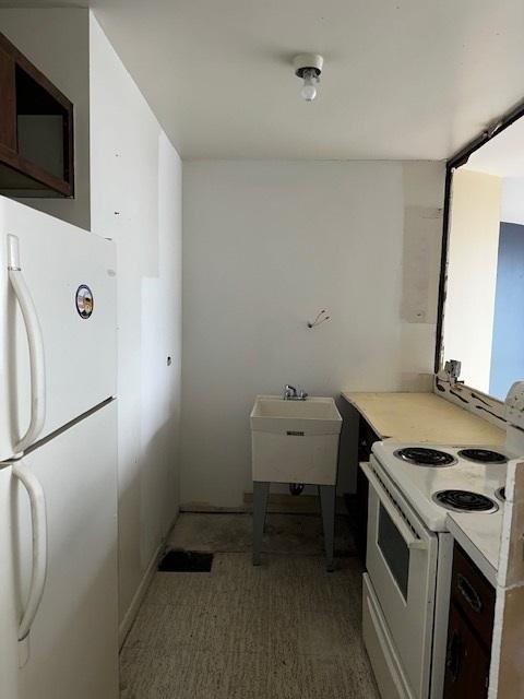 kitchen featuring white appliances, wood-type flooring, and sink