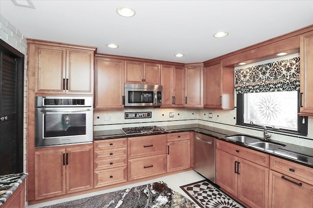 kitchen featuring appliances with stainless steel finishes, tasteful backsplash, sink, dark stone countertops, and light tile patterned floors