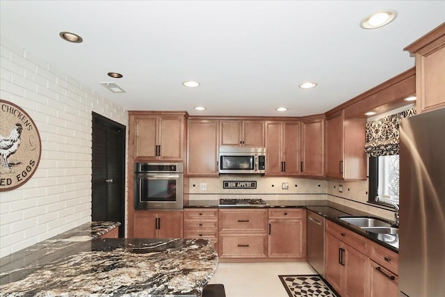 kitchen with appliances with stainless steel finishes, tasteful backsplash, sink, dark stone countertops, and kitchen peninsula