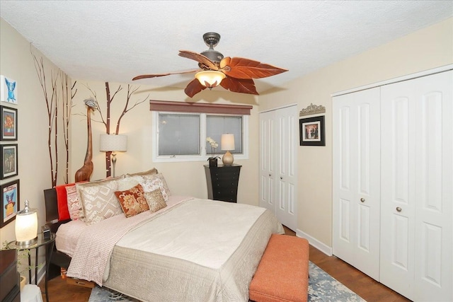 bedroom featuring ceiling fan, two closets, a textured ceiling, and hardwood / wood-style flooring