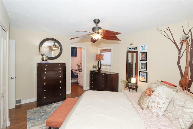 bedroom featuring dark wood-type flooring, a textured ceiling, ceiling fan, and ensuite bath