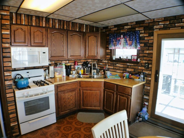 kitchen with sink, white appliances, and brick wall