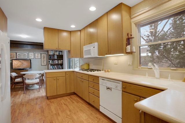 kitchen featuring light brown cabinetry, sink, kitchen peninsula, white appliances, and light hardwood / wood-style flooring