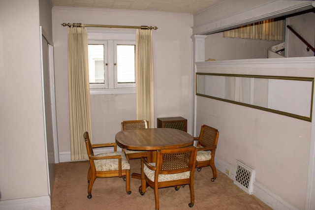 dining area with crown molding and light carpet