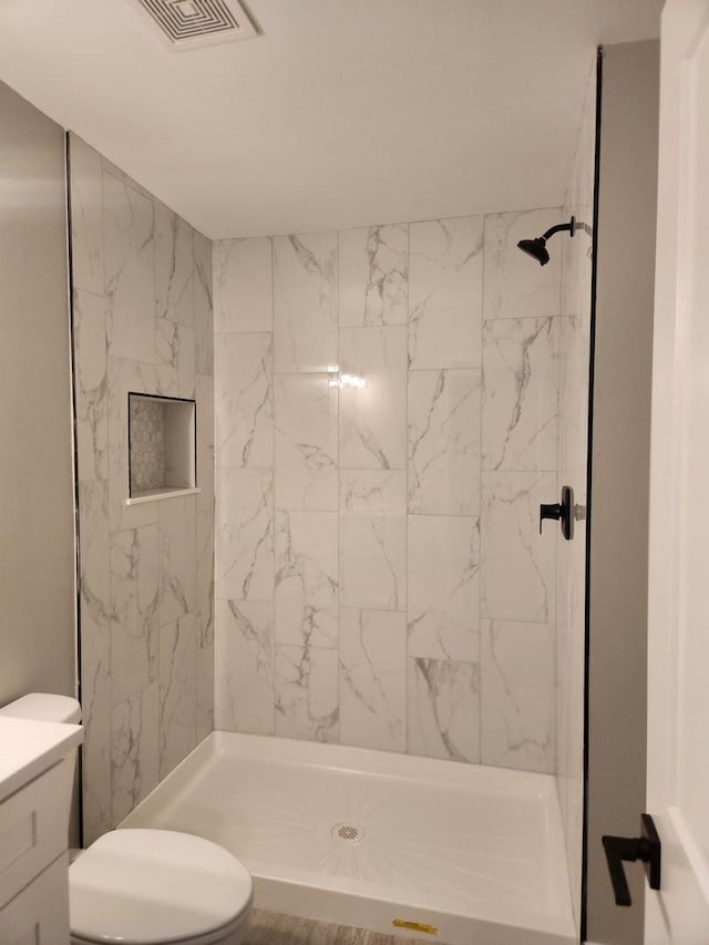 bathroom featuring tiled shower, vanity, and toilet