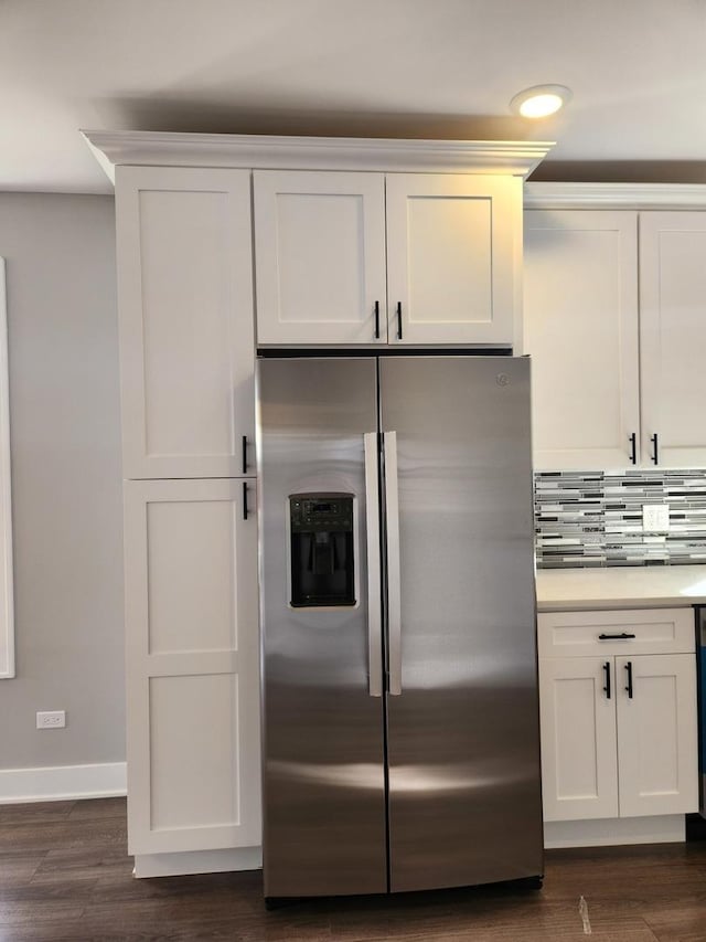 kitchen with stainless steel refrigerator with ice dispenser, dark hardwood / wood-style flooring, white cabinets, and backsplash