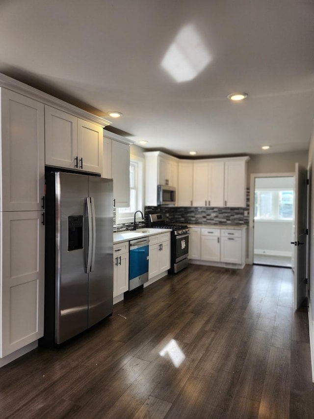 kitchen featuring sink, white cabinetry, stainless steel appliances, dark hardwood / wood-style flooring, and decorative backsplash