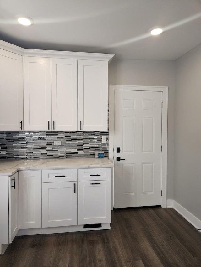 kitchen featuring tasteful backsplash, dark hardwood / wood-style floors, light stone countertops, and white cabinets