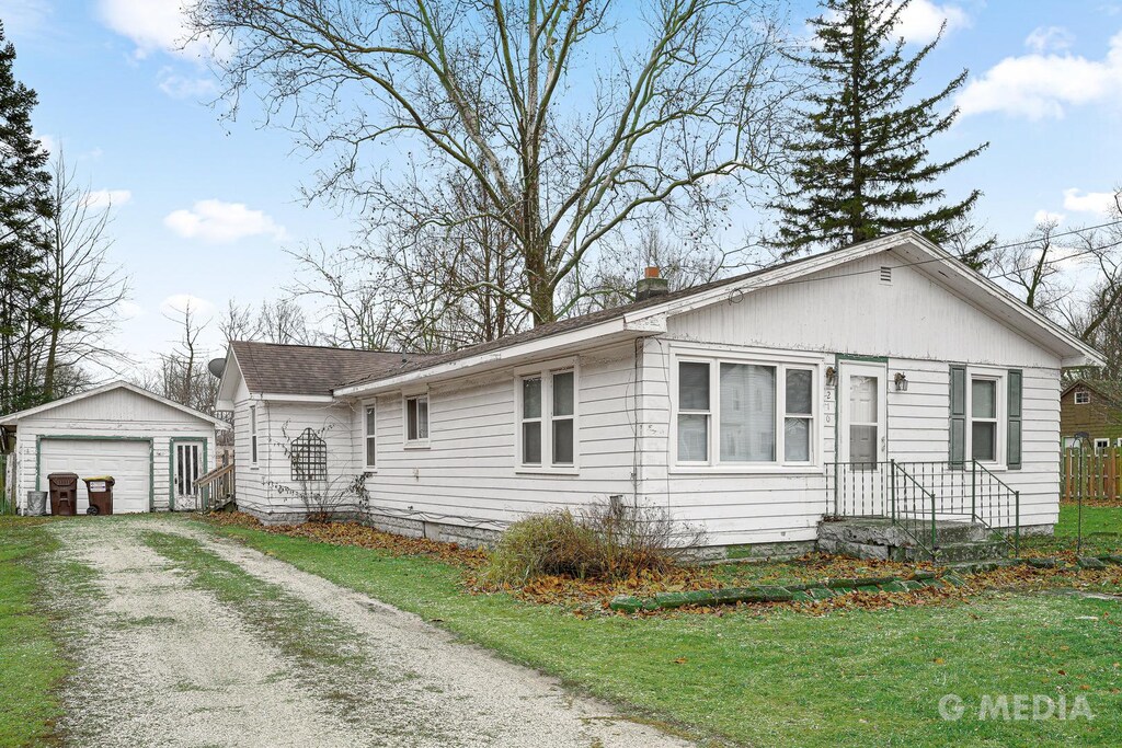 view of front facade with a garage, an outbuilding, and a front lawn