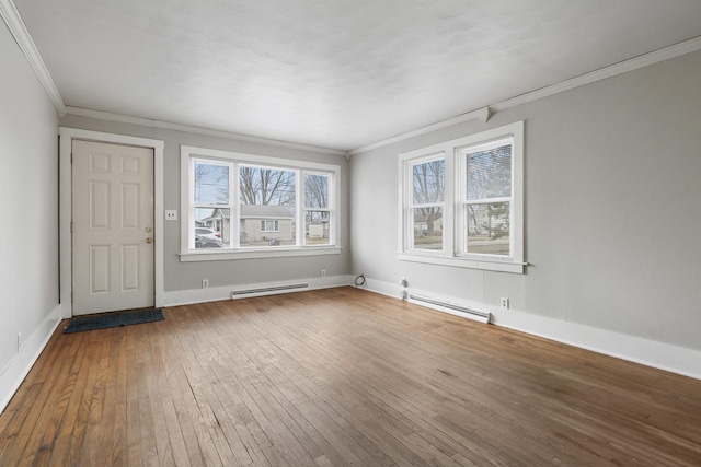 empty room featuring hardwood / wood-style floors, a baseboard heating unit, and a wealth of natural light