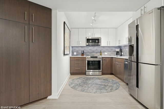 kitchen with dark brown cabinetry, white cabinetry, light hardwood / wood-style flooring, stainless steel appliances, and decorative backsplash