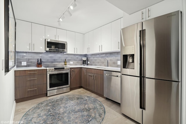 kitchen with appliances with stainless steel finishes, sink, dark brown cabinets, and white cabinets