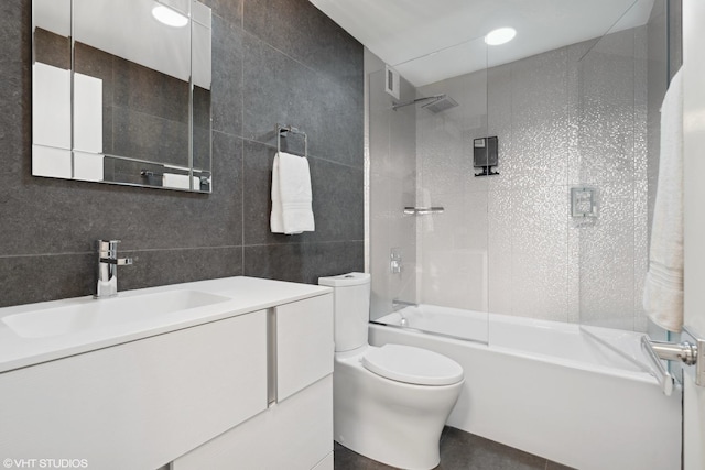 full bathroom with vanity, toilet, tile walls, and tiled shower / bath