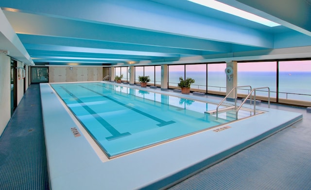 pool at dusk with a skylight and a water view