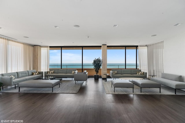 living room with floor to ceiling windows, a water view, dark wood-type flooring, and plenty of natural light