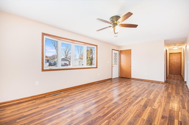 spare room with visible vents, ceiling fan, baseboards, and wood finished floors