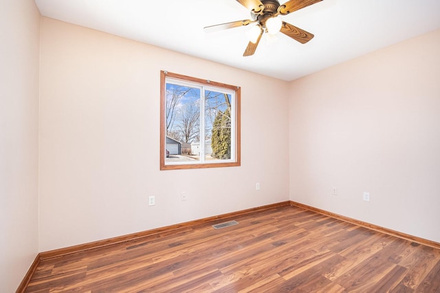 unfurnished room with a ceiling fan, visible vents, baseboards, and wood finished floors