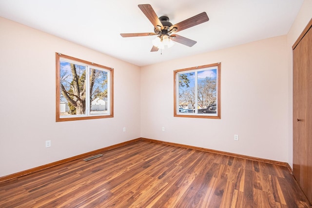 unfurnished bedroom featuring ceiling fan, wood finished floors, visible vents, baseboards, and a closet