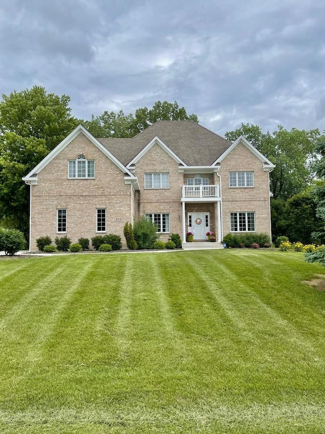 view of front facade with a front yard and a balcony